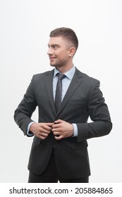 Waistup Portrait Of Young Smiling Handsome Businessman Putting On Suit Jacket Looking Aside Isolated On White