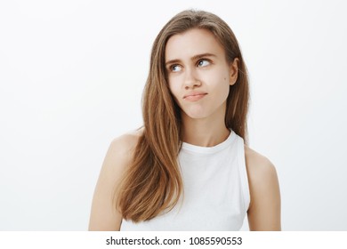 Waist-up Shot Of Unimpressed Indifferent Attractive Woman With Fair Hair, Rolling Eyelids And Pulling Lips Down, Feeling Bored, Being On Boring Date, Standing Annoyed And Tired Over Gray Background