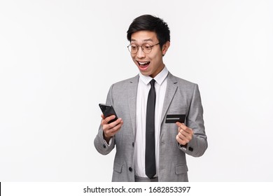 Waist-up Of Surprised Excited, Handsome Asian Male Entrepreneur Seeing Special Discount At Shopping Application, Hurry Up And Enter Credit Card Digit Numbers To Mobile Phone Display, White Background