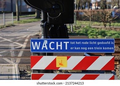 Wait sign at a railway crossing in the Netherlands. The signs says "WAIT until the red light goes out, another train may come" - Shutterstock ID 2137244213
