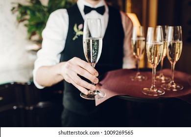 waiter brings glasses of champagne and  tray