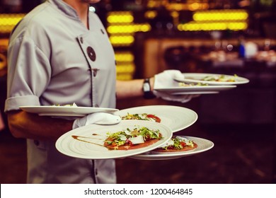 The waiter brings meal with sauce and dressing in restaurant close-up