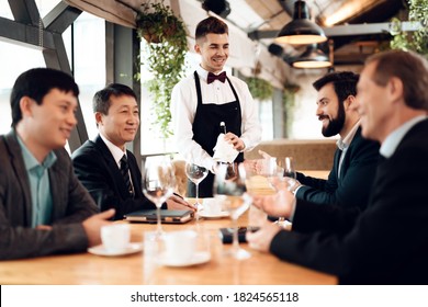 The waiter brought good wine for business people in a restaurant. Business people sitting at a table in a restaurant and discussing business.