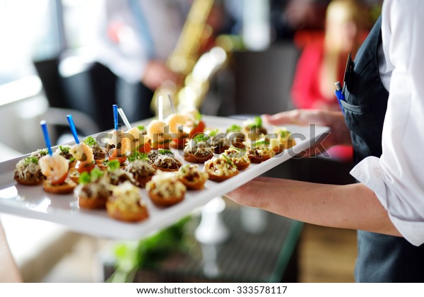 Waiter carrying plates with meat dish\
on some festive event, party or wedding\
reception