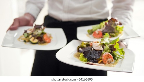 Waiter, carrying three plates with a rich salad - Powered by Shutterstock