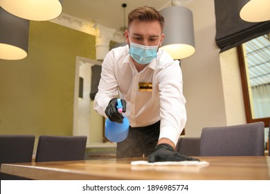 Waiter Cleaning Table With Rag And Detergent In Restaurant. Surface Treatment During Coronavirus Quarantine