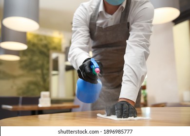 Waiter cleaning table with rag and detergent in restaurant, closeup. Surface treatment during coronavirus pandemic - Powered by Shutterstock