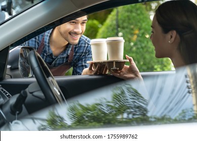 Waiter giving hot coffee cup with disposable tray and bakery bag through car window to customer at drive thru service station. Drive thru is popular service after coronavirus covid-19 pandemic.