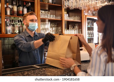 Waiter Giving Packed Takeout Order To Customer In Restaurant. Food Service During Coronavirus Quarantine