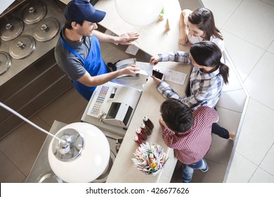 Waiter Giving Receipt To Female Customer Standing With Family - Powered by Shutterstock