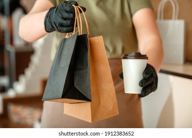 Waiter giving takeout meal while city covid 19 lockdown, coronavirus shutdown. Unrecognizable woman waiter, female hands in gloves work with takeaway orders. Food coffee delivery