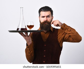 Waiter with glass and bottle of whiskey on tray. Service and restaurant catering concept. Man with beard holds alcohol on white background. Barman curling mustache serves scotch or brandy.