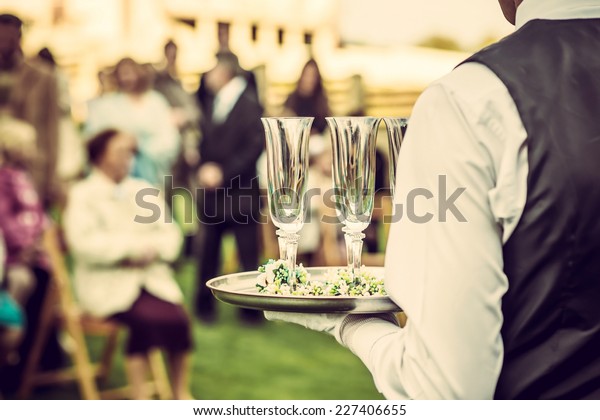Waiter with glasses on the tray at wedding\
ceremony, waiting for\
champagne
