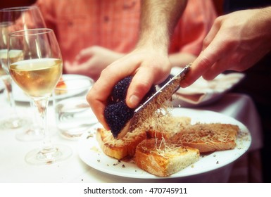 Waiter is grating black truffle on bread with olive oil, toned image