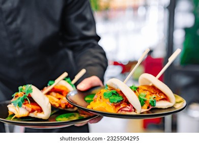 waiter hand hold Gua bao, steamed buns with pork belly and vegetable - Powered by Shutterstock