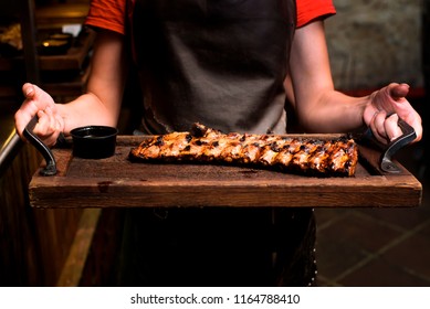 waiter hold tray with grilled pork ribs, Sliced prime rib roast on a wood cutting board, Spicy hot grilled spare ribs from a summer BBQ, Barbecue ribs as top view on an old vintage tray - Powered by Shutterstock