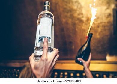 Waiter is holding bottles of vodka and champagne up at a party