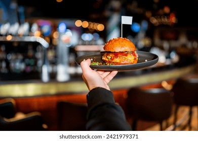 waiter holding plate with burger at pub - Powered by Shutterstock