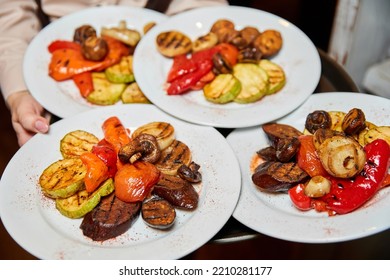 Waiter Holding Plates With Chopped Grilled Vegetables