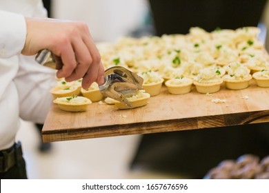 Waiter Holding Wooden Plate With Canapes And Using Utensil Tong Food Service Concept.