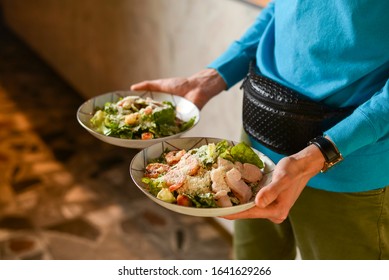Waiter holds two plates with Italian salad with cured ham, jamon, prosciutto, fresh vegetables and parmesan cheesein a restaurant. - Shutterstock ID 1641629266