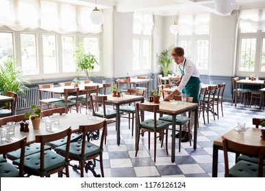 Waiter Laying Tables In Empty Restaurant