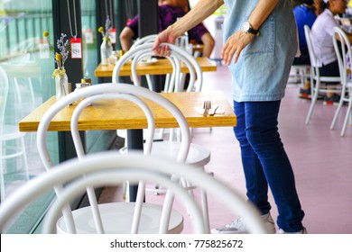 Waiter Organizing Chairs In Modern Cafe In Australia. Server Working In Bright Australian Cafeteria With Contemporary Decor In Rhodes, Sydney Australia.