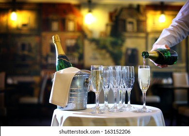 a waiter pouring champagne in the glasses in the restaurant
