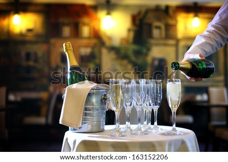 a waiter pouring champagne in the glasses in the restaurant