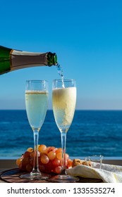 Waiter Pouring Champagne, Prosecco Or Cava In Two Glasses On Outside Terrace With Sea View  Close Up