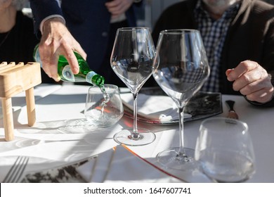 Waiter Pouring Mineral Water From Bottle Into A Glass, In Restaurant, Food Concept, Two Empty Wineglass On Table