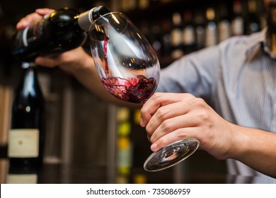 Waiter pouring red wine in a glass.