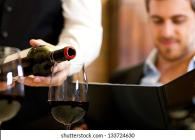 Waiter Pouring Red Wine To A Man