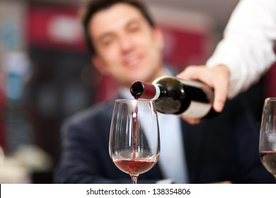 Waiter Pouring Red Wine To A Man 