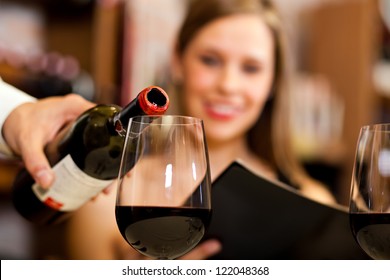 Waiter Pouring Red Wine To A Woman