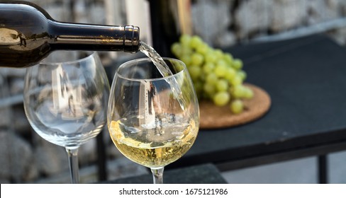 Waiter Pouring White Wine On Outdoor Cafe Terrace In Sunny Summer Day