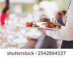 The waiter prepares the festive table. dishes on the table. Waiter serving table in the restaurant preparing to receive guests. Waiter carrying plates with meat dish on some festive event.