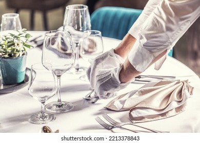 The waiter prepares the festive table in the hotel restaurant.