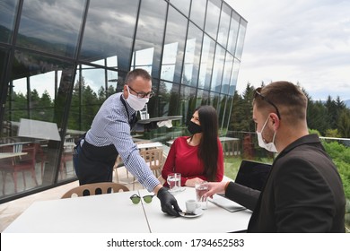 Waiter With Protective Medical Mask And Gloves Serving Guest With Coffee At An Outdoor Bar Café Or Restaurant New Normal Concept Reopening After Quarantine