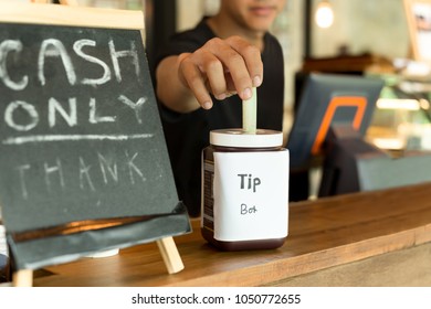 Waiter Putting Money Into Tip Box In Cafe