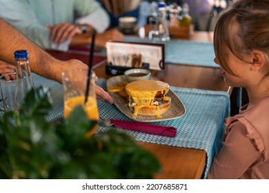 The Waiter In The Restaurant Brings Lunch To The Whole Family Of Three. Family Launch Concept.