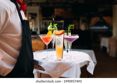 The waiter serves cocktails on a tray