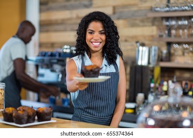 Waiter serving a cup cake at counter in cafe