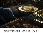 a waiter is serving food wearing blue gloves. On the plate there was green rice, some pieces of green vegetables such as long beans, and pieces of meat. The food served is Indonesian food