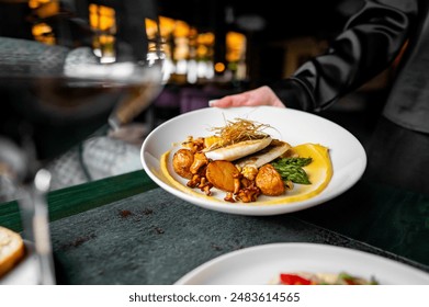 Waiter serving gourmet fish dish with golden garnish in an upscale restaurant. - Powered by Shutterstock