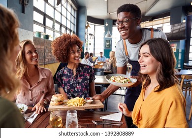 Официант обслуживает группу подруг, встречающихся за напитками и едой в ресторане