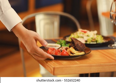 Waiter serving meals in restaurant, close up - Shutterstock ID 552652240