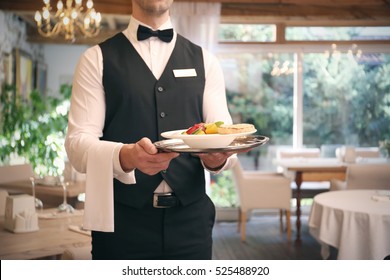 Waiter serving salad at restaurant, close up view
