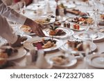 Waiter serving table in the restaurant preparing to receive guests. Waiter carrying plates with meat dish on some festive event. 