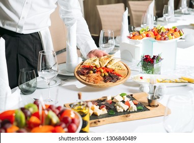 Waiter serving table in the restaurant preparing to receive guests. - Shutterstock ID 1306840489